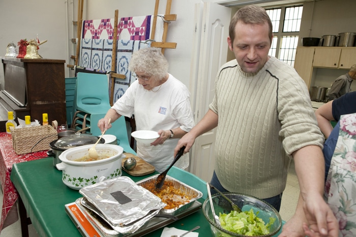 Evelyn Kidd, left, and Michael Gould, Chair of the Beach Interfaith Outreach Lunch at Kingston Road United Church serve lunch to a group of residents on Jan. 4. PHOTO: Phil Lameira / Beach Metro News