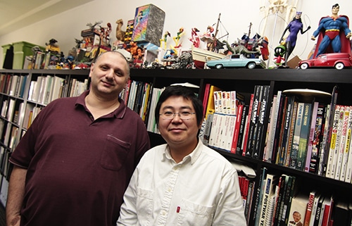Comics creator George Gatsis, left, and Ding Ding, a producer on Gatsis’ forthcoming animated feature, Seven, stand by shelves of comics and action figures in Gatsis’ Gerrard Street office. “That’s what’s left of my personal collection,” said Gatsis, chuckling. “My parents decided to throw all my comic books away at one point.” PHOTO: Andrew Hudson
