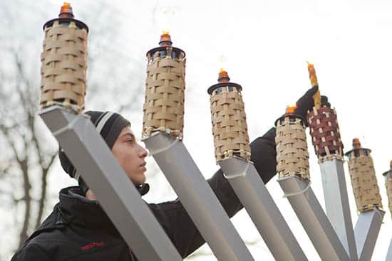 Adam Kline, 13, lights the Menorah. A crowd of people gathered on Dec. 21 in front of Toronto Fire Station 227 for the lighting of the Menorah. The gathering was preceded by a tour of the firehall and hot chocolate and was organized by the Chabad Jewish Centre in the Beach. PHOTO: Phil Lameira