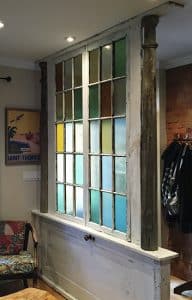 Christine Roberts created this divider to separate an entry from a living room. It was built from vintage parts including stained glass windows, an old door, and a pair of columns to finish off the ends. PHOTO: Christine Roberts